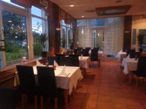 a dining room with white tables and chairs and windows at Central Hotel Winnenden in Winnenden