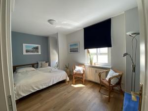a bedroom with a bed and two chairs and a window at Villa Seeblick Warnemünde - Fewo mit Meerblick und Balkon direkt am Strand für 2-4 Pers in Rostock