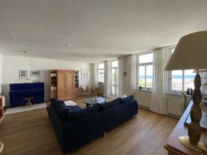 ein Wohnzimmer mit einem blauen Sofa und einem Tisch in der Unterkunft Villa Seeblick Warnemünde - Fewo mit Meerblick und Balkon direkt am Strand für 2-4 Pers in Rostock