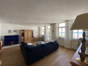 a living room with a blue couch and a table at Villa Seeblick Warnemünde - Fewo mit Meerblick und Balkon direkt am Strand für 2-4 Pers in Rostock