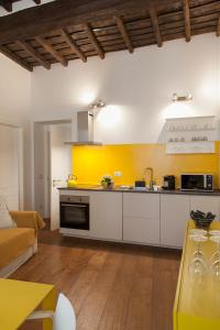 a kitchen with white cabinets and a yellow wall at Palazzetto de Lante Appartamento Pinta in Rome