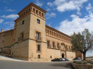 a large brick building with cars parked in front of it at Parador de Alcañiz in Alcañiz