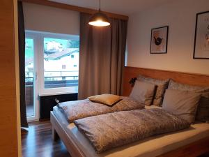 Schlafzimmer mit einem Bett und einem großen Fenster in der Unterkunft Exklusiv Apartment Sonnenalp in Niederau