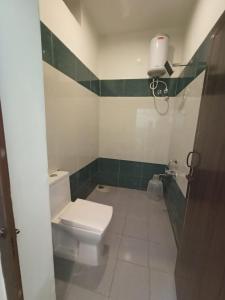 a bathroom with a white toilet and green tiles at Sushmika Villas in Yercaud