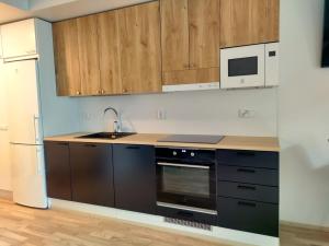 een keuken met houten kasten, een wastafel en een koelkast bij Fully Equipped New Apartment With Free Parking in Tampere