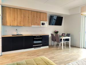 a kitchen with black cabinets and a table with chairs at Fully Equipped New Apartment With Free Parking in Tampere