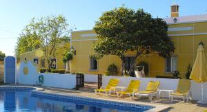 a group of yellow chairs next to a swimming pool at Monte dos Avós in Querença