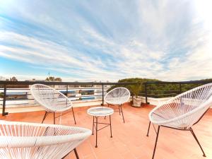 three white chairs on a balcony with a view at Casa Natura Gava Beach in Barcelona