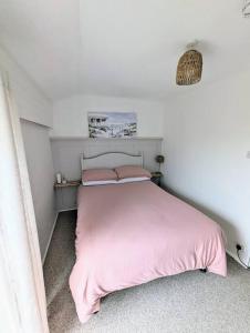 een slaapkamer met een roze bed en een roze deken bij No.7 Perran View in St. Agnes 