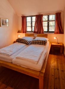 two twin beds in a bedroom with two windows at Hof & Gut Jesteburg in Jesteburg
