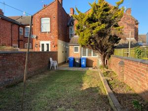 a yard with a brick wall and a tree at Salisbury House in Kettering