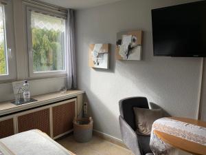 Zimmer mit einem TV, einem Stuhl und einem Fenster in der Unterkunft Gästehaus Villa Kreativ Susanne Lay in Bad Münder am Deister
