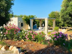 einen Garten mit Blumen und einem Pavillon in der Unterkunft NEW SHEPHERD HOUSE, CAROVIGNO, 2 Adults + 1 child in Carovigno