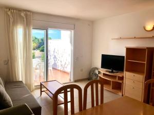 a living room with a couch and a television and a table at Duplex Ancla in L'Ametlla de Mar