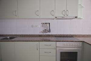 a kitchen with white cabinets and a stove top oven at Duplex Ancla in L'Ametlla de Mar