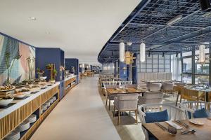 un ristorante con tavoli e sedie in legno e un corridoio lungo di NH Collection Dubai The Palm a Dubai