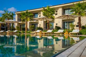 a resort with a swimming pool with chairs and umbrellas at Palaia Hotel Datça in Datca