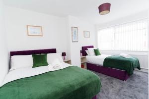 two beds in a room with green and white at Foxwood Stays in Leeds