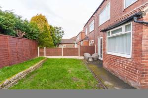 a backyard with a brick house with a yard with two toilets at Foxwood Stays in Leeds