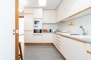 una cocina con armarios blancos y fregadero en Quinta da Barca Guest House, en Esposende