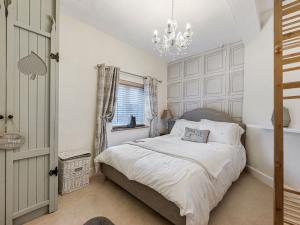 a bedroom with a bed and a chandelier at Wisteria Cottage in Nantwich