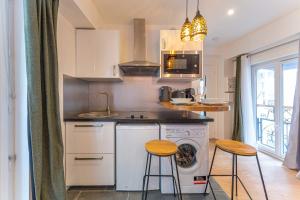 kuchnia z pralką i 2 stołkami w obiekcie Cosy studio - 2P - Center of Paris w Paryżu