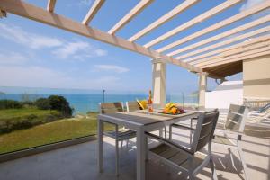 a table and chairs on a patio with a view of the ocean at Diamond Arillas Luxury Apartments in Arillas