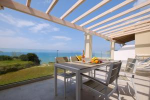 un tavolo e sedie su un patio con vista sull'oceano di Diamond Arillas Luxury Apartments a Arillas