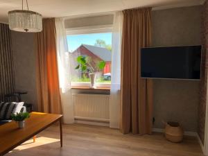 sala de estar con ventana y TV de pantalla plana en Villa på lantlig idyll i Källunga, Herrljunga, en Herrljunga