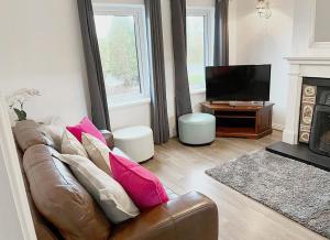 un salon avec un canapé en cuir brun et une télévision dans l'établissement Burren Seaside Lodge, à Ballyvaughan