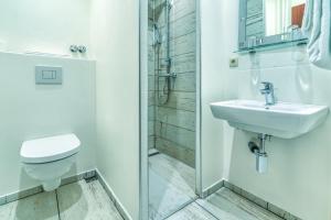 La salle de bains est pourvue de toilettes, d'un lavabo et d'une douche. dans l'établissement Guesthouse Beckmann, à Göttingen