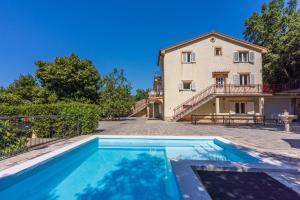 a villa with a swimming pool in front of a house at Apartments NEVEN in Grižane