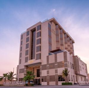 a building with palm trees in front of it at AlRayah Hotel in Jazan