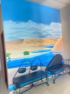 une chambre avec deux chaises devant une fresque murale dans l'établissement Pousada Mineira, à Barreirinhas