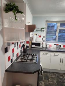 a small kitchen with a stove and a microwave at Rent Unique the Beeches 2bed in Crawley