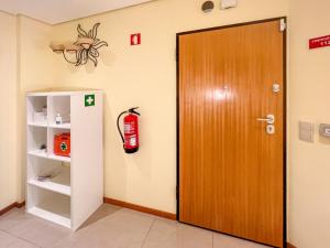 eine Tür in einem Raum mit einem Feuerlöscher an der Wand in der Unterkunft Appartement - Plage de Furadouro - Rico's Homes in Ovar