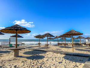 eine Gruppe von Sonnenschirmen am Strand mit dem Meer in der Unterkunft Appartement - Plage de Furadouro - Rico's Homes in Ovar