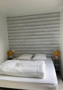 a bed with two pillows in a bedroom with two lamps at Charming eco-lodge with heated pool and jacuzzi all year round in Charente-Marit in Les Mathes