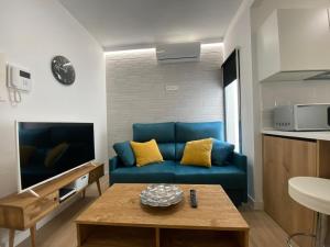 Sala de estar con sofá azul y mesa de centro en Lovely Private Suite Center, en Málaga
