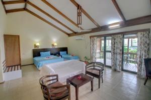 Honiara Hotel في هونيارا: غرفة نوم بسرير وطاولة وكراسي