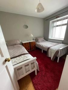 a bedroom with two beds and a red carpet at Port Lodge Northern Ireland in Portaferry