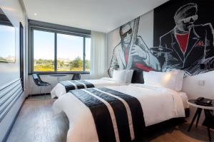 two beds in a hotel room with a painting on the wall at HF Fénix Music in Lisbon