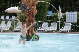 um rapaz numa piscina ao lado de uma fonte de água em Campeggio Europa Silvella em San Felice del Benaco
