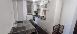 a kitchen with white cabinets and a table in it at Dacia Apartment in Timişoara