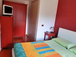 ein Schlafzimmer mit einem Bett und einem TV an einer roten Wand in der Unterkunft Nel cuore della maiella in Palombaro