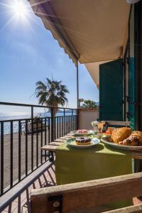 a table with plates of food on a balcony with the beach at Loft Balcone Sul Mare in Letojanni