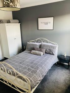 a bed in a bedroom with a gray wall at 2 bedroomed house close to Cleethorpes seafront in Cleethorpes