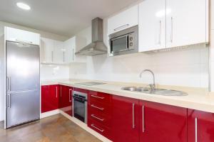 La cuisine est équipée de placards rouges et d'un réfrigérateur en acier inoxydable. dans l'établissement Dream Sea Apartments, à Almerimar