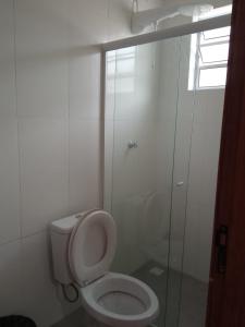 a bathroom with a toilet and a glass shower at Associação Sabesp Ilha Comprida in Ilha Comprida