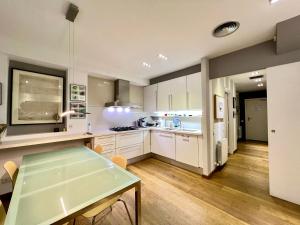 a kitchen with white cabinets and a dining table at ArtlifeBCN Urban Oasis Apartment in Barcelona